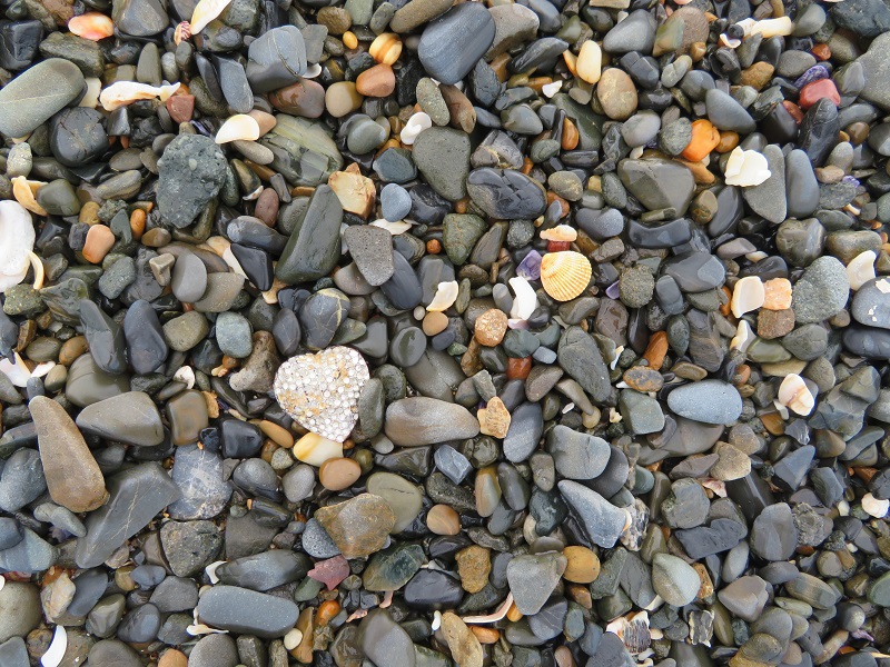 Heart from a locket among pebbles 