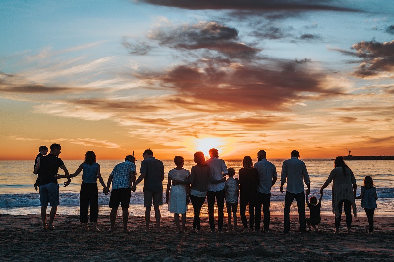 silhouetted group of people on beach at sunset